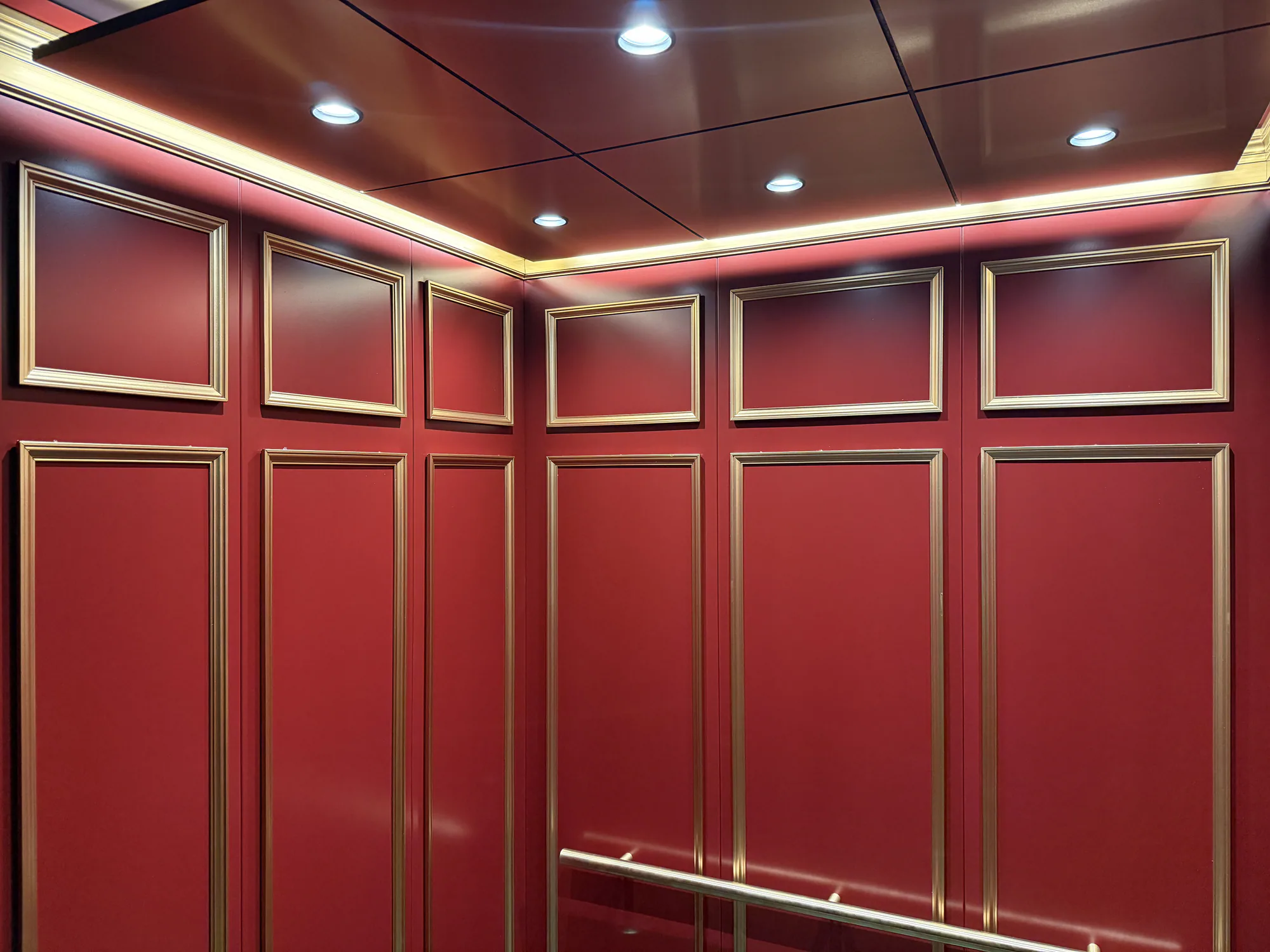 Wide view of a red paneled Chicago elevator cab with framed wall details