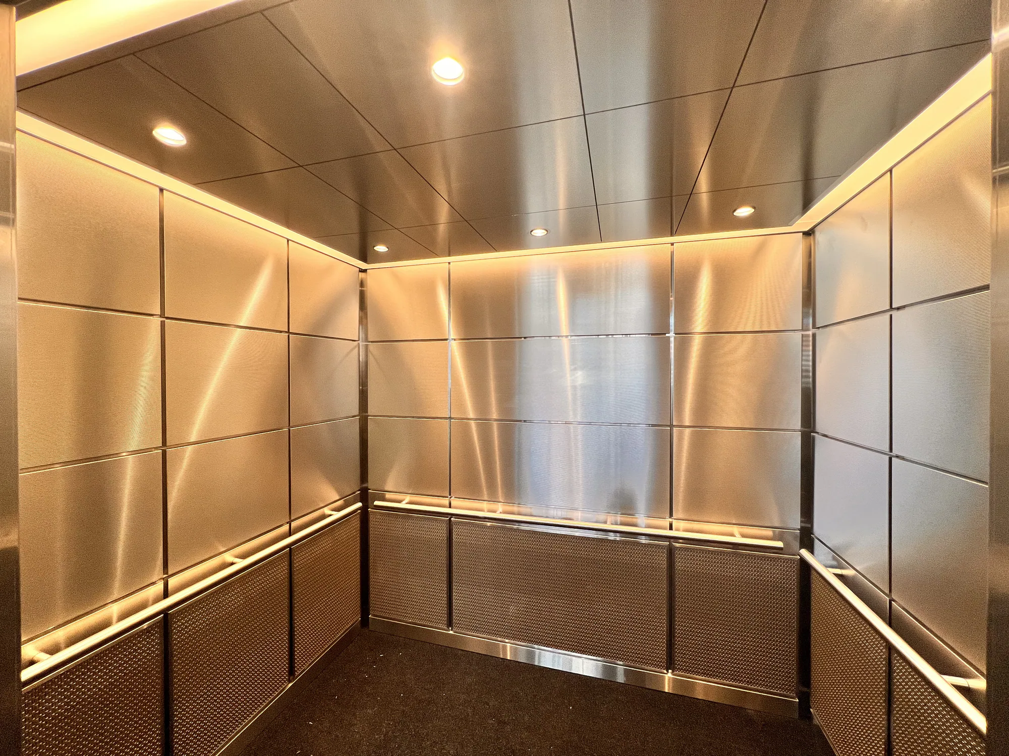Wide Northwestern hospital elevator interior with warm reflective metal panels